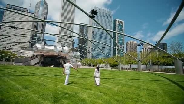 Vackra par i kärlek gå på gräset bredvid skyskrapor i Downtown Chicago på en solig dag — Stockvideo