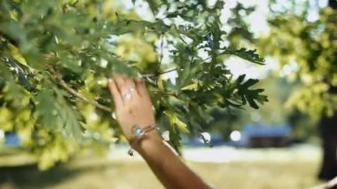 Genç bir kız gülümseyerek ve sevindirici güneşli Park, ağaç dalları geliyor.