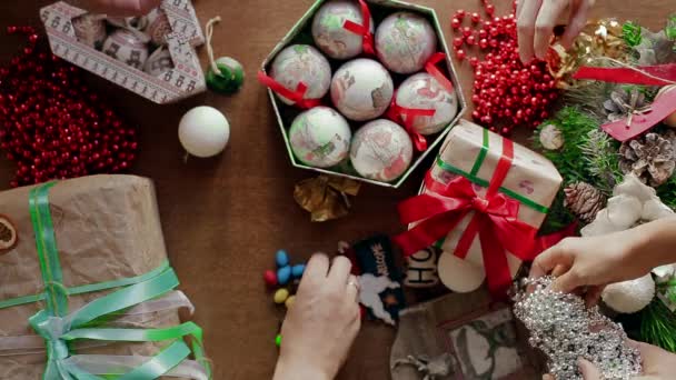 Molte persone impacchettano e spostano regali sul tavolo e pillole colorate divise . — Video Stock