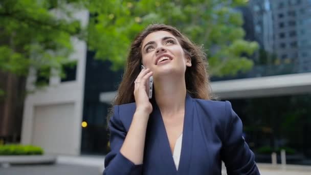 Jovencita de pie al aire libre debajo del edificio y mirando al cielo y dicho por teléfono . — Vídeos de Stock