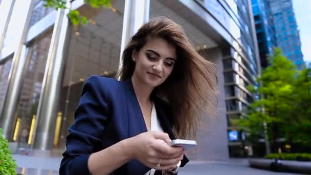 Business Lady w Blue Jacket stojący w pobliżu budynku, wybierz kontakt i rozmowa przez telefon. Uśmiechy. — Wideo stockowe