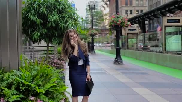 Una joven vestida formalmente sentada bajo un árbol y hablando por teléfono . — Vídeos de Stock