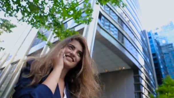 Uma menina de pé perto do edifício e conversando ao telefone . — Vídeo de Stock