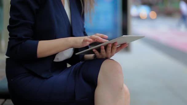 Une jeune fille assise sur un banc à l'extérieur du bureau et travaillant sur la tablette . — Video