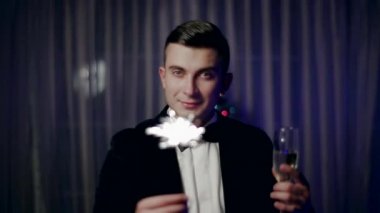 bir cam ve maytap yakınındaki bir Noel ağacı ile genç bir adam duruyor.