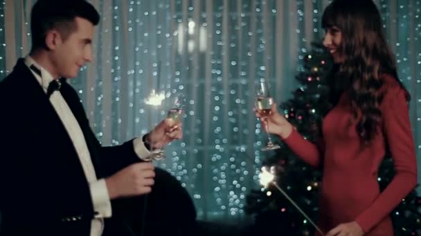 Un joven y una niña se acercan entre sí con champán y luces de bengala . — Vídeos de Stock
