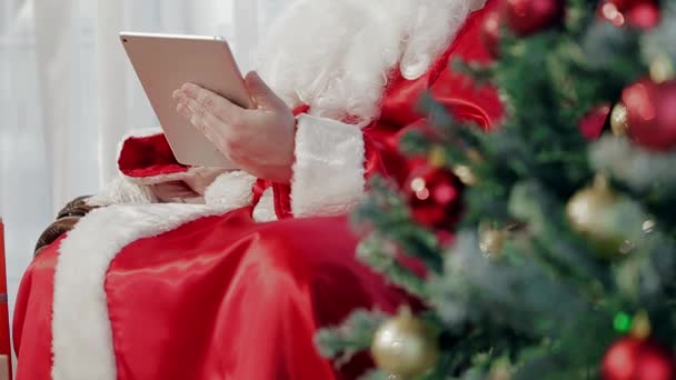 Typskylten, håller en Man i röd kostym nära en julgran. — Stockvideo