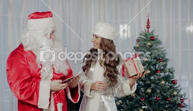 Noel Baba ve Noel ağacın yanında, birbirlerine hediyeler ve iletişim gösterisi ayakta kar kızlık.