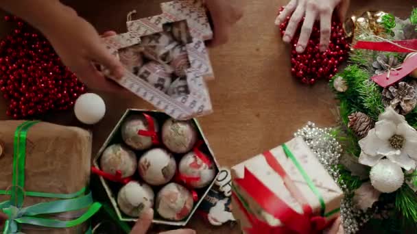 いくつかの手クリスマス ボールはテーブルの上の箱に梱包、多くのクリスマス アクセサリー. — ストック動画