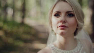 Damat ve gelin ormanın arka planında öpüşüyor.