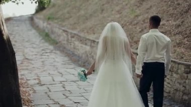 Damat ve gelin ormanın arka planında öpüşüyor.