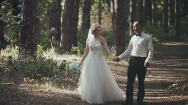 Damat ve gelin ormanın arka planında öpüşüyor.