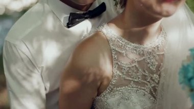 Damat ve gelin ormanın arka planında öpüşüyor.