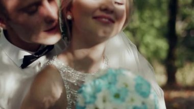 Damat ve gelin ormanın arka planında öpüşüyor.