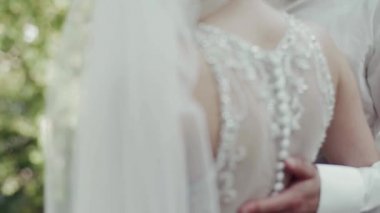 Damat ve gelin ormanın arka planında öpüşüyor.