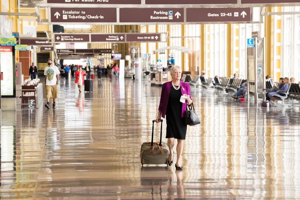 Passagiere gehen durch einen hellen Flughafen — Stockfoto