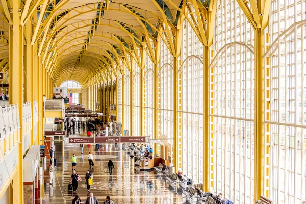 Passagiere gehen durch einen hellen Flughafen — Stockfoto