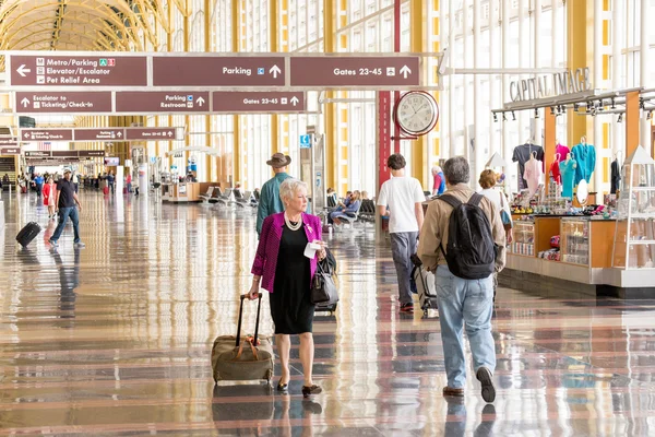 Passagiere gehen durch einen hellen Flughafen — Stockfoto