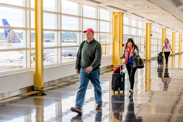 Passagiere gehen durch einen hellen Flughafen — Stockfoto