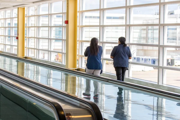 Passagiere gehen durch einen hellen Flughafen — Stockfoto