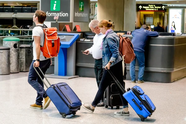 Ludzie chodzą z bagażu na lotnisku — Zdjęcie stockowe