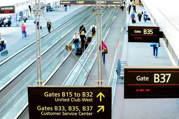 People walking with luggage in airport — Stock Photo, Image