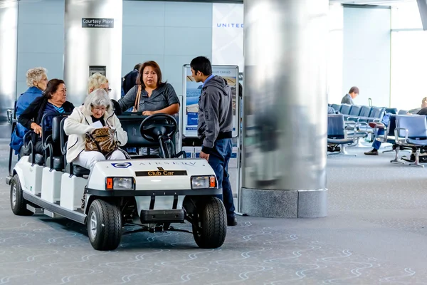 Pessoas e passageiros andando em carrinhos motorizados no aeroporto — Fotografia de Stock