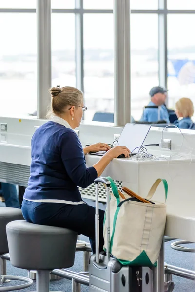 Kvinna sitter vid den bärbara datorn laddningsstation på en flygplats — Stockfoto