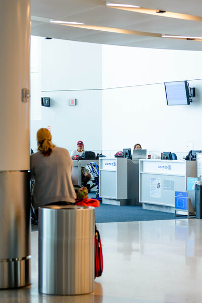 woman seated on a trash can waiting for her flight in an airport
