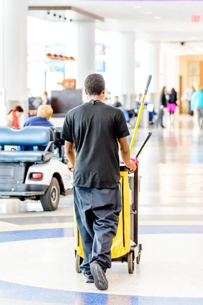 Pulizia uomo spingendo carrello in un aeroporto — Foto Stock