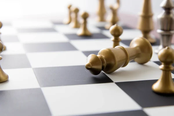 Chess game - fallen gold king on chessboard — Stock Photo, Image