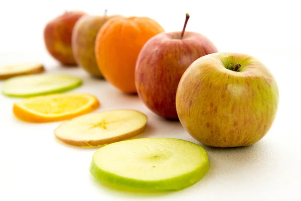 Line of apples and slices with one orange — Stock Photo, Image