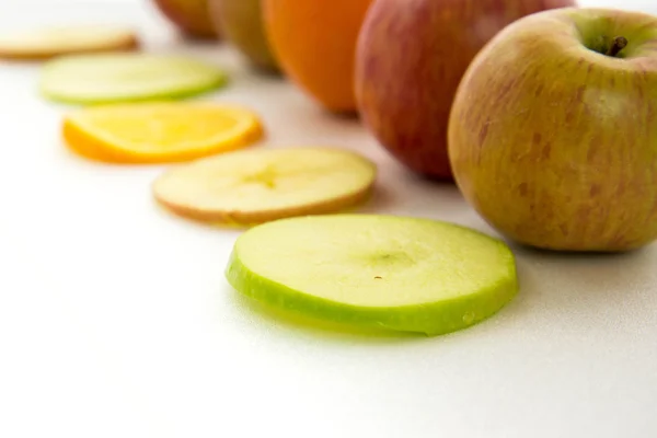 Line of apples and slices with one orange — Stock Photo, Image