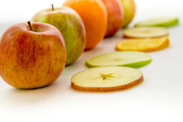 Line of apples and slices with one orange — Stock Photo, Image