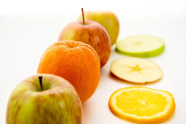 Line of apples and slices with one orange — Stock Photo, Image