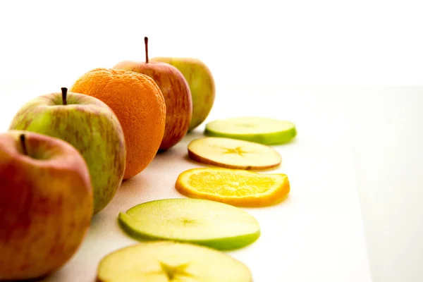 Line of apples and slices with one orange — Stock Photo, Image