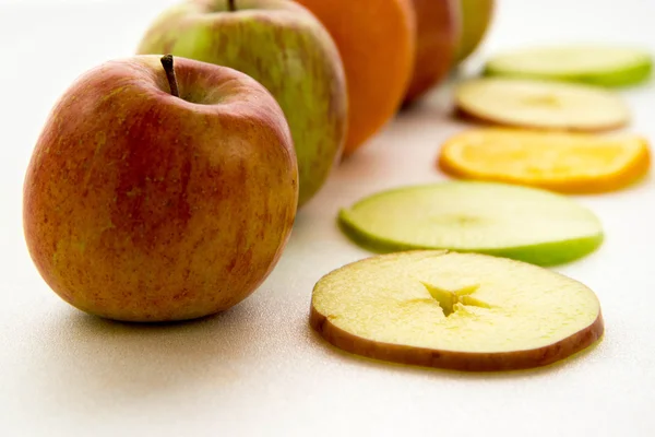 Line of apples and slices with one orange — Stock Photo, Image