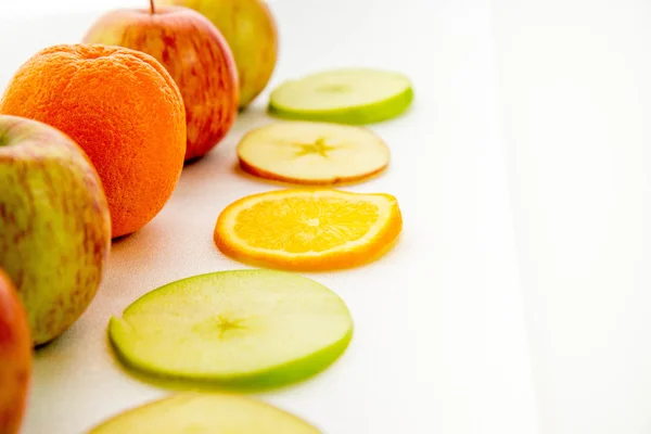 line of apples and slices with one orange