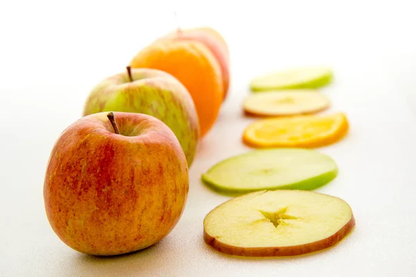 Line of apples and slices with one orange — Stock Photo, Image