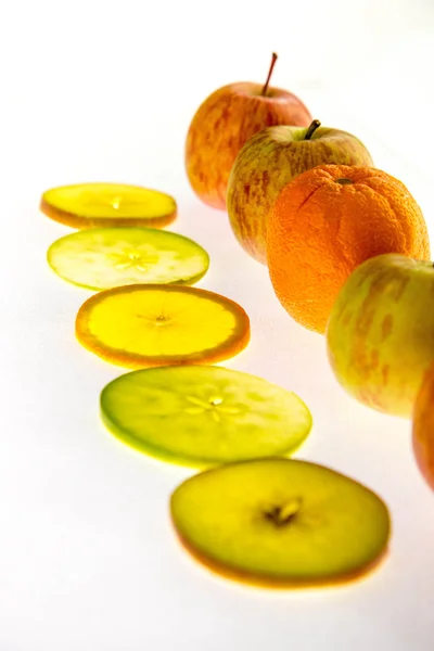 Linha de maçãs e fatias retroiluminadas com uma laranja — Fotografia de Stock