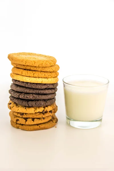 Variety of cookies stacked and glass of milk — Stock Photo, Image