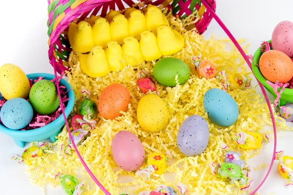 Cesto pasquale con uova colorate, pulcini gialli e caramelle — Foto Stock
