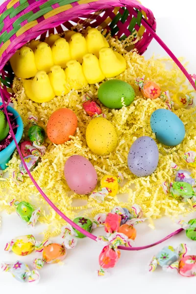 Osterkorb mit bunten Eiern, gelben Küken und Süßigkeiten — Stockfoto