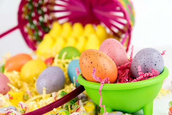 Osterkorb mit bunten Eiern, gelben Küken und Süßigkeiten — Stockfoto
