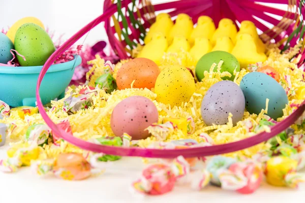 Пасхальная корзина с цветными яйцами, желтыми цыплятами и конфетами — стоковое фото