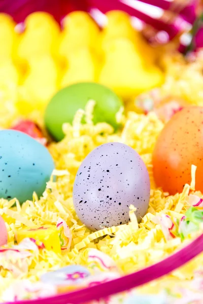 Osterkorb mit bunten Eiern, gelben Küken und Süßigkeiten — Stockfoto