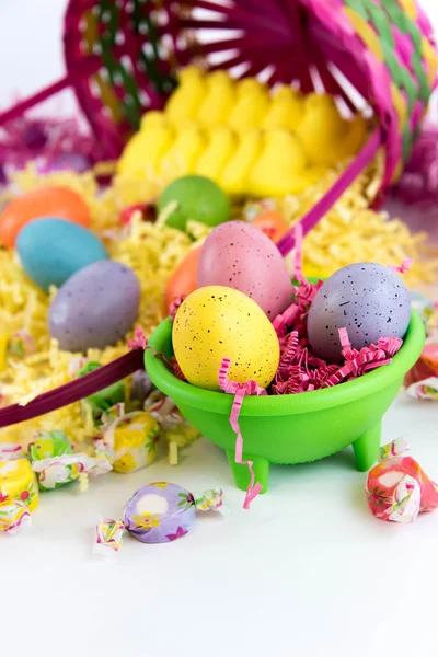 Osterkorb mit bunten Eiern, gelben Küken und Süßigkeiten — Stockfoto