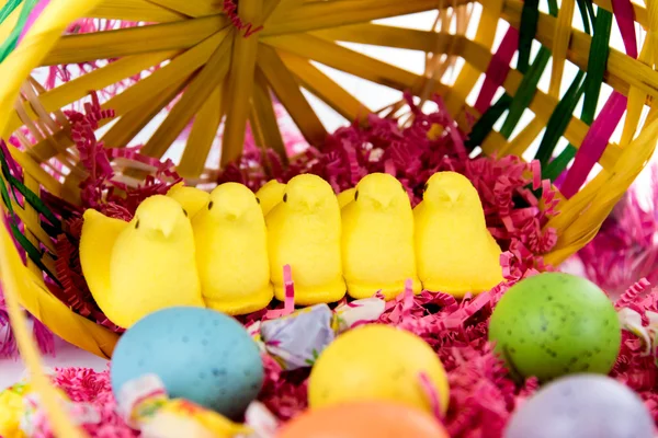 Osterkorb mit bunten Eiern, gelben Küken und Süßigkeiten — Stockfoto