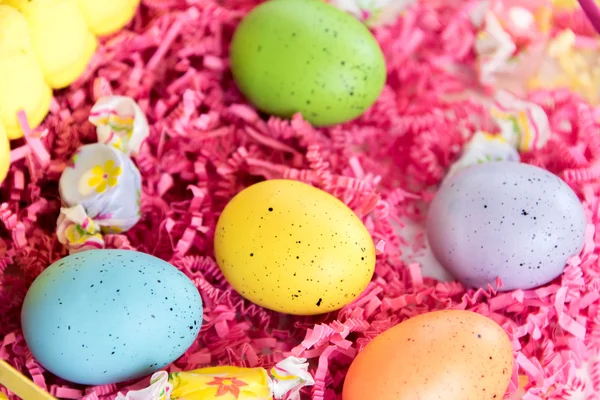 Osterkorb mit bunten Eiern, gelben Küken und Süßigkeiten — Stockfoto