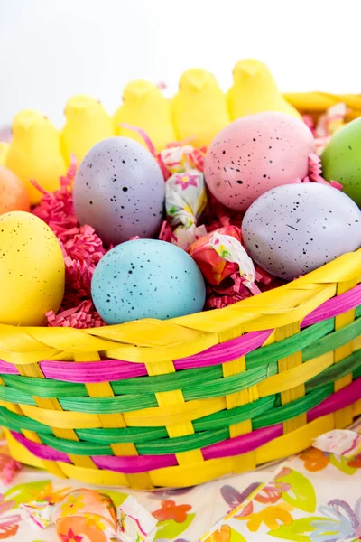 Osterkorb mit bunten Eiern, gelben Küken und Süßigkeiten — Stockfoto